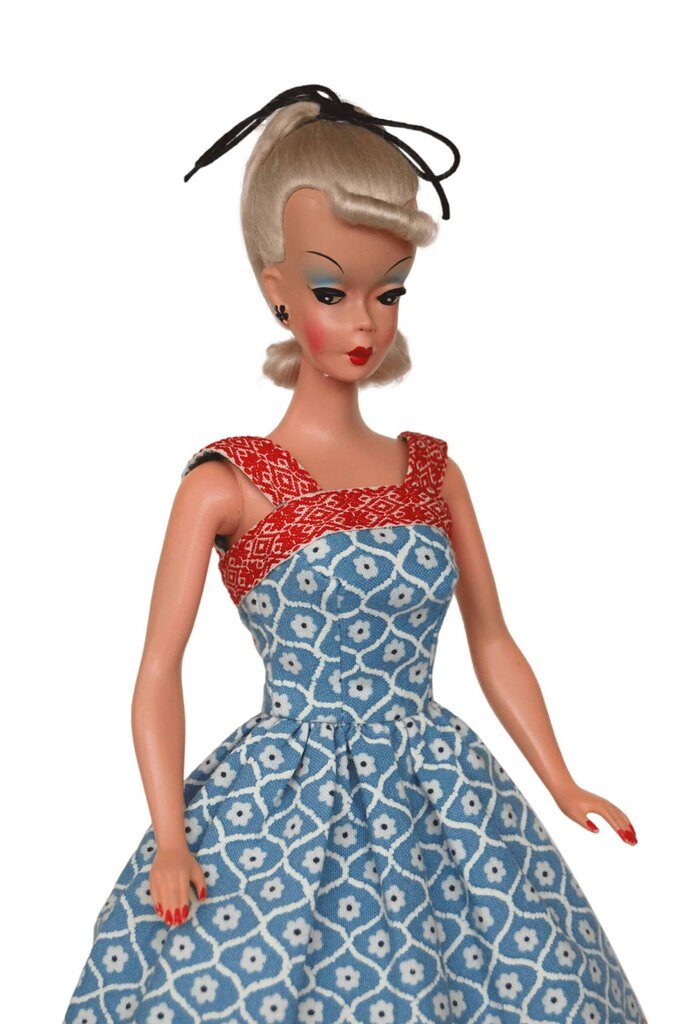 Bild Lilli doll in a blue floral dress with a red cross-strap bodice and pleated skirt, reflecting vintage-inspired craftsmanship.