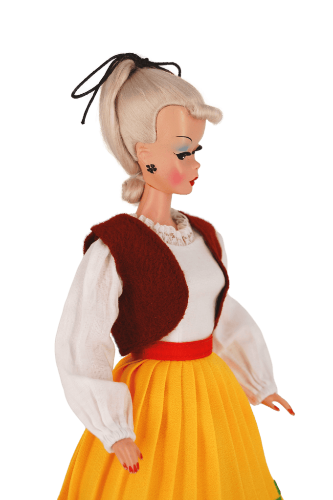 Bild Lilli doll in a folk-inspired outfit with a white blouse, wool vest, and yellow pleated skirt, capturing retro European charm.