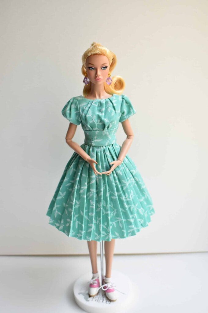 Mint green vintage doll dress with white botanical print, puffed sleeves, fitted bodice, and full pleated skirt. Retro-inspired handmade collectible fashion for dolls.