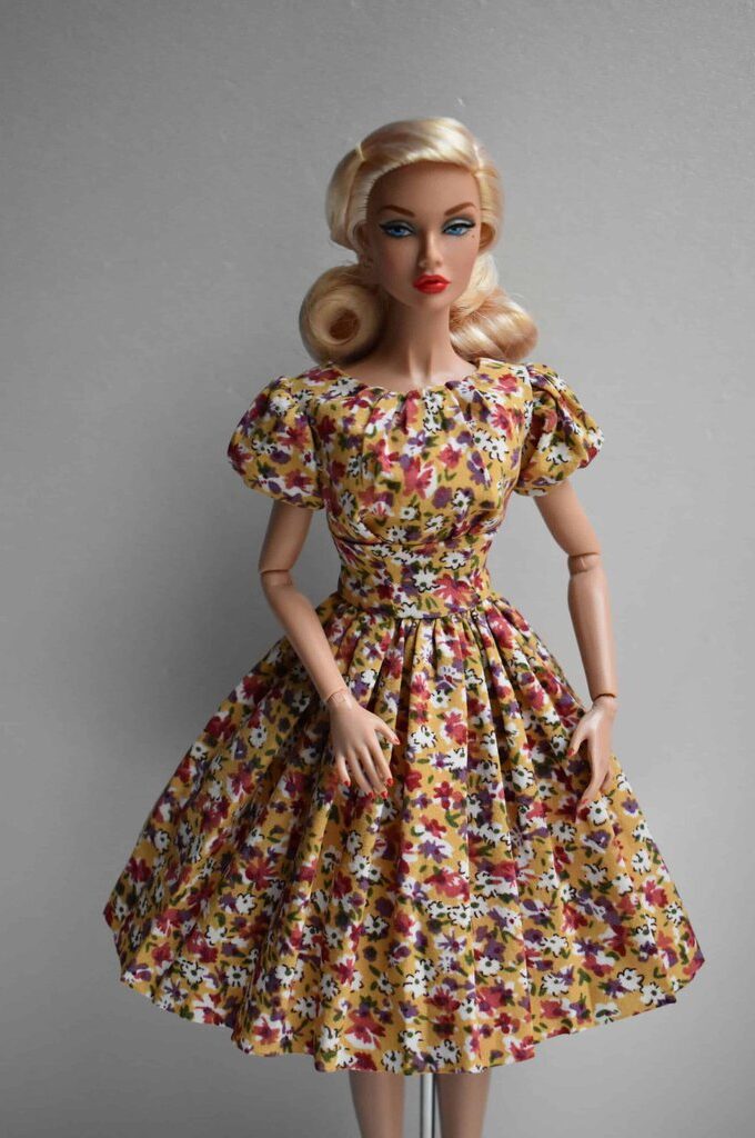 Vintage-style mustard floral doll dress featuring puffed sleeves, structured bodice, and a flowing pleated skirt with delicate floral accents.