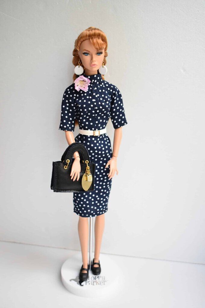 Classic navy polka dot dress featuring three-quarter sleeves, a gathered collar, and a cinched waist for a timeless silhouette.