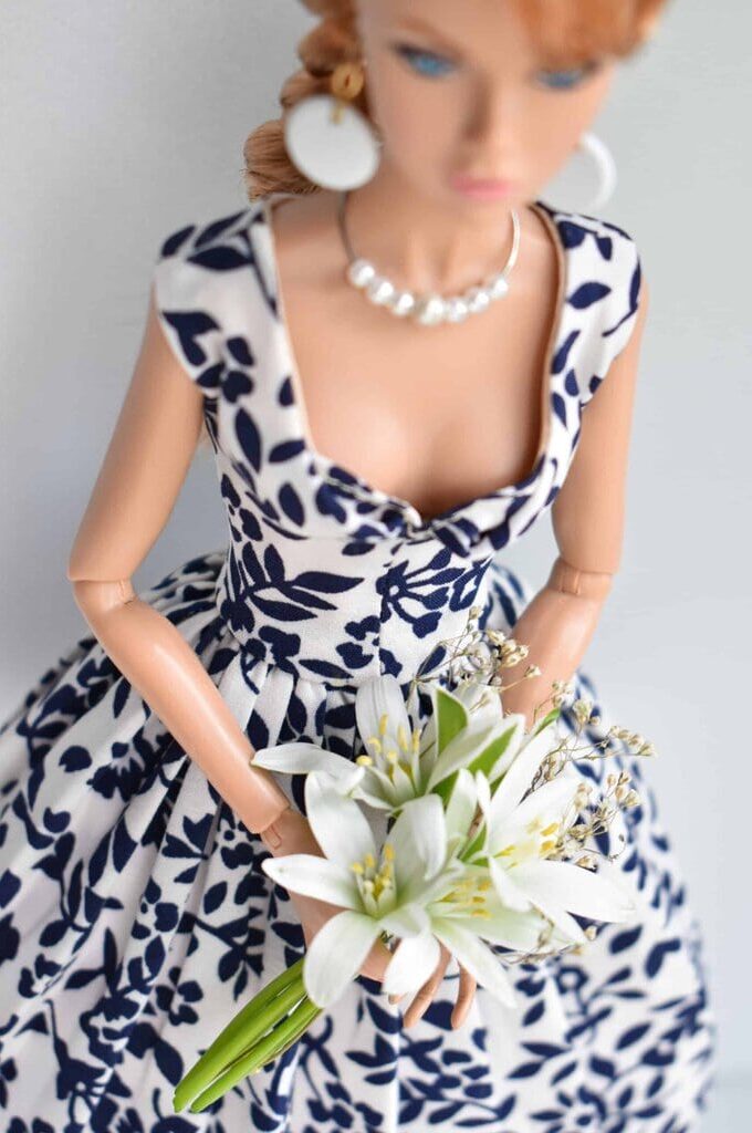 Elegant white dress with navy floral print, sweetheart neckline, and full pleated skirt for a timeless vintage-inspired look.